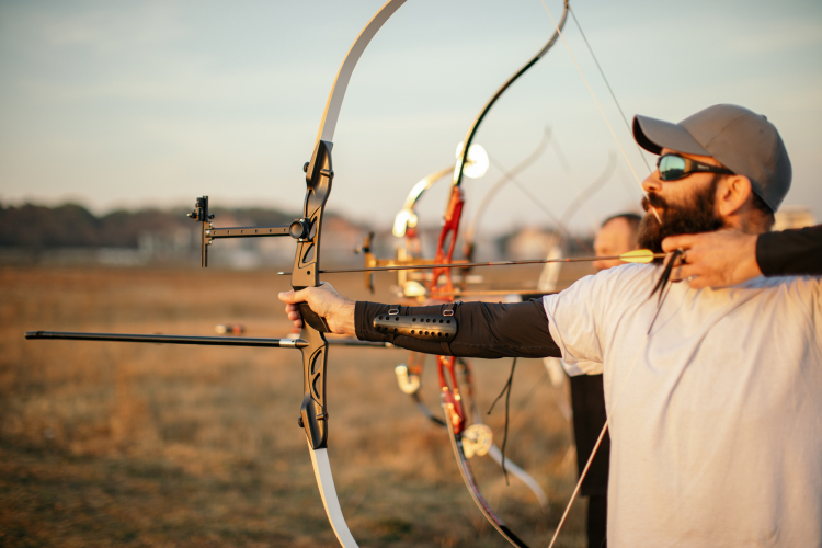Sport de précision et vue : homme pratiquant du tir à l'arc et portant des lunettes de soleil pour protéger ses yeux.
